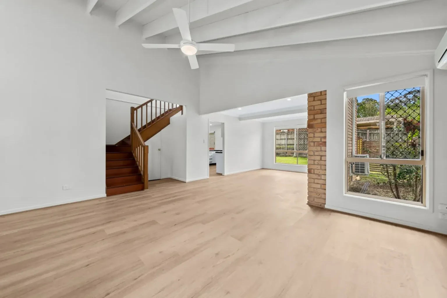 Living room with raked ceiling and timber staircase on BestBuys Neutral Oak hybrid flooring