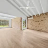 Unfurnished living room with raked ceiling and brick wall on BestBuys Neutral Oak hybrid flooring