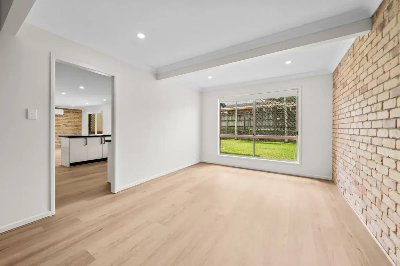 Unfurnished dining room showing BestBuys Neutral Oak hybrid flooring next to a brick wall
